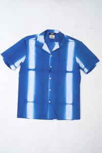 Wakame Shirt Blue Batik featuring a blue, striped, and white tie-dye pattern with short sleeves, designed for quick drying and crafted for versatile menswear.